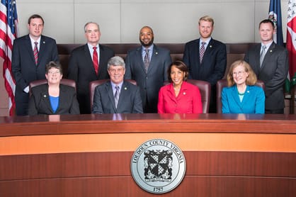 Nine members of the board of supervisors behind wooden desk